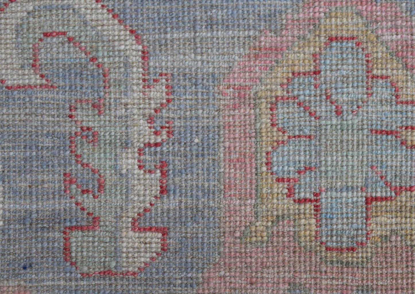 A close-up view of a handwoven transitional Oushak rug featuring a floral pattern in soft tones.