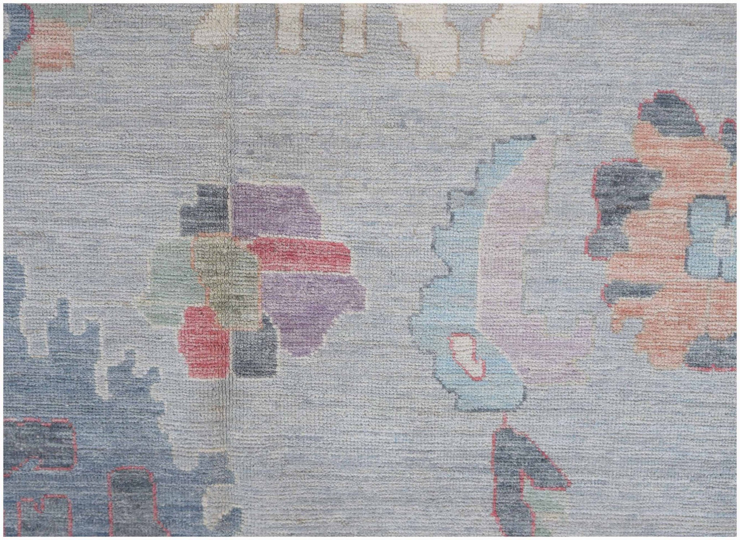 A transitional Oushak rug featuring a light blue field with abstract floral motifs in muted tones.