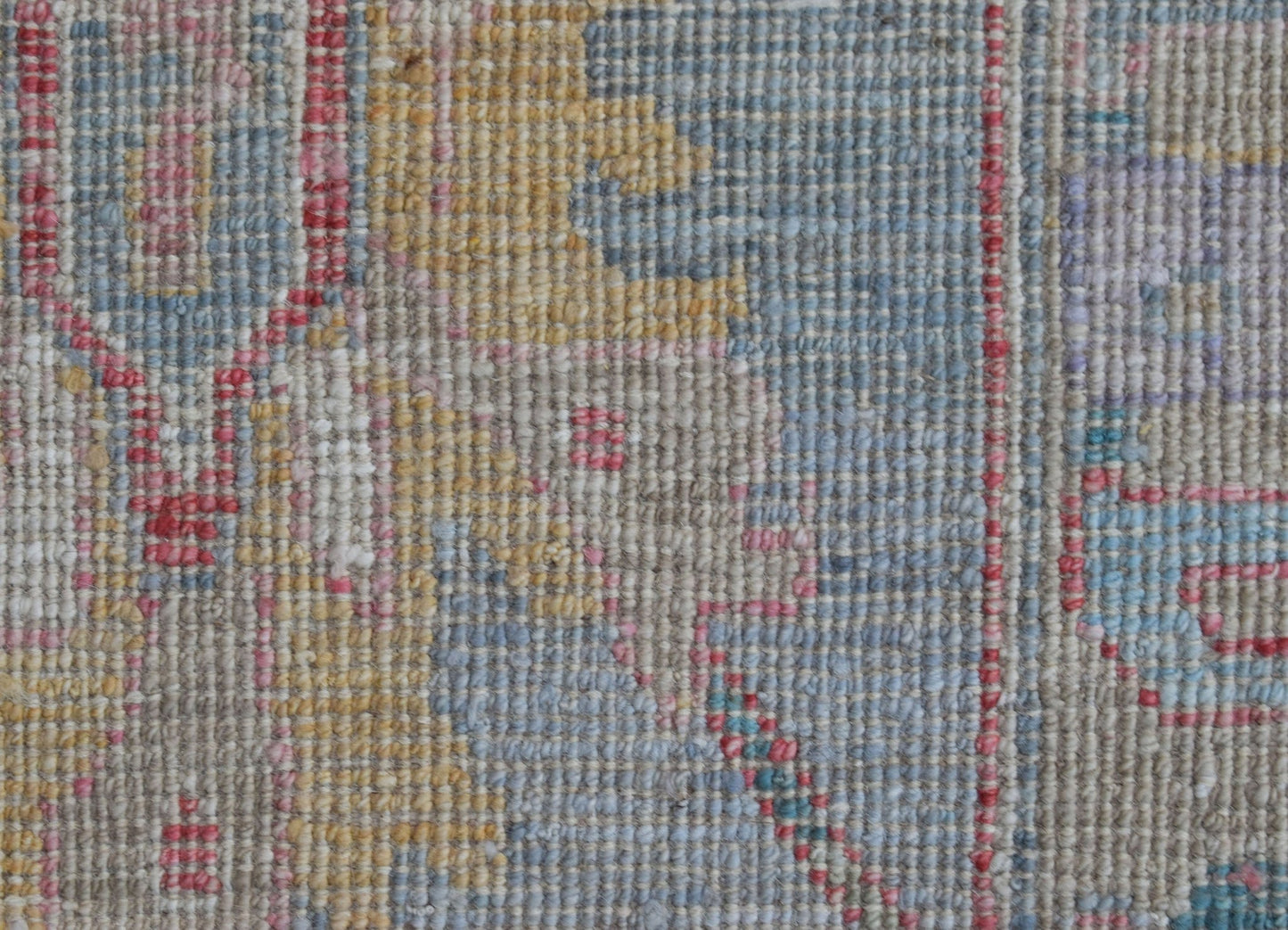 A close-up view of a handwoven wool rug featuring a transitional pattern in muted tones.