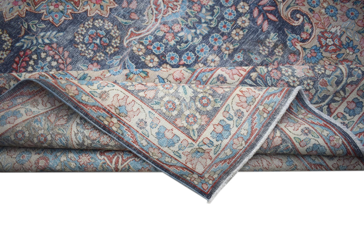 A vintage Persian Kerman rug featuring a blue field with intricate floral patterns and a border.