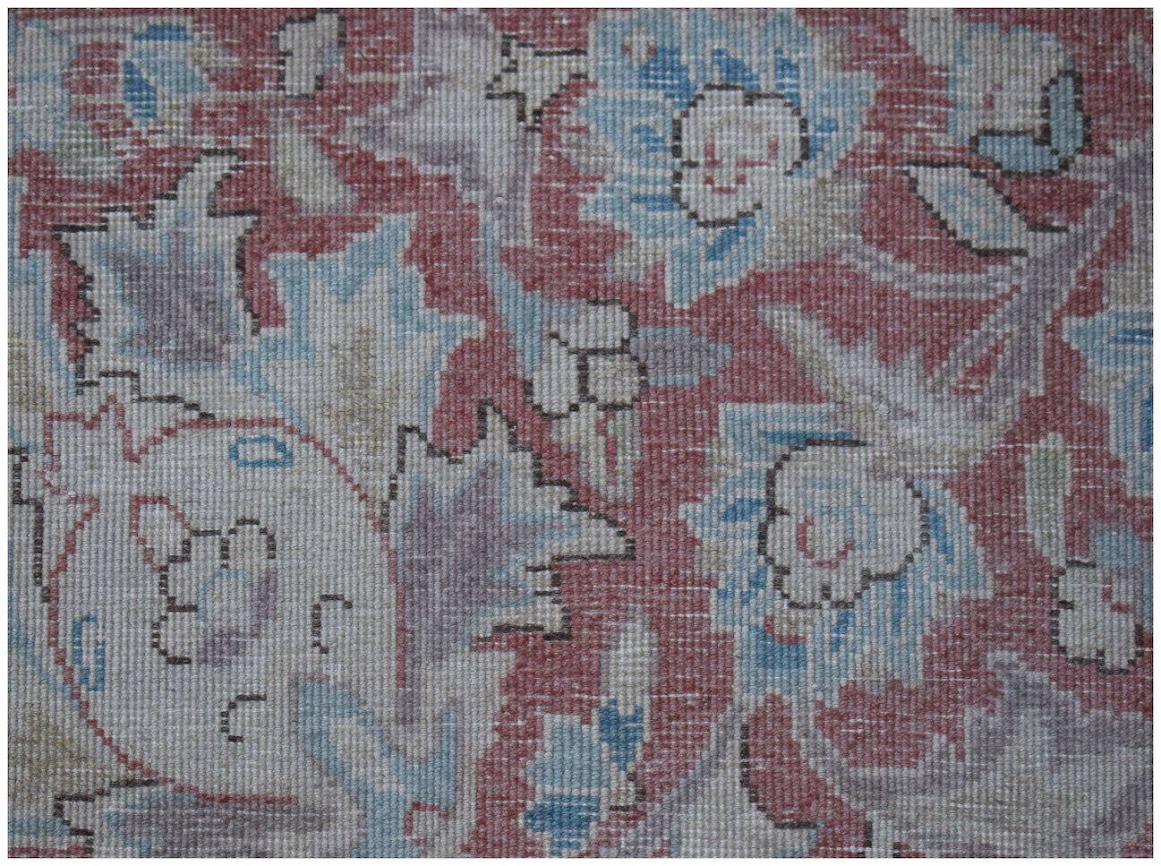 A close-up of a vintage Persian Kerman rug featuring intricate floral patterns in muted tones.