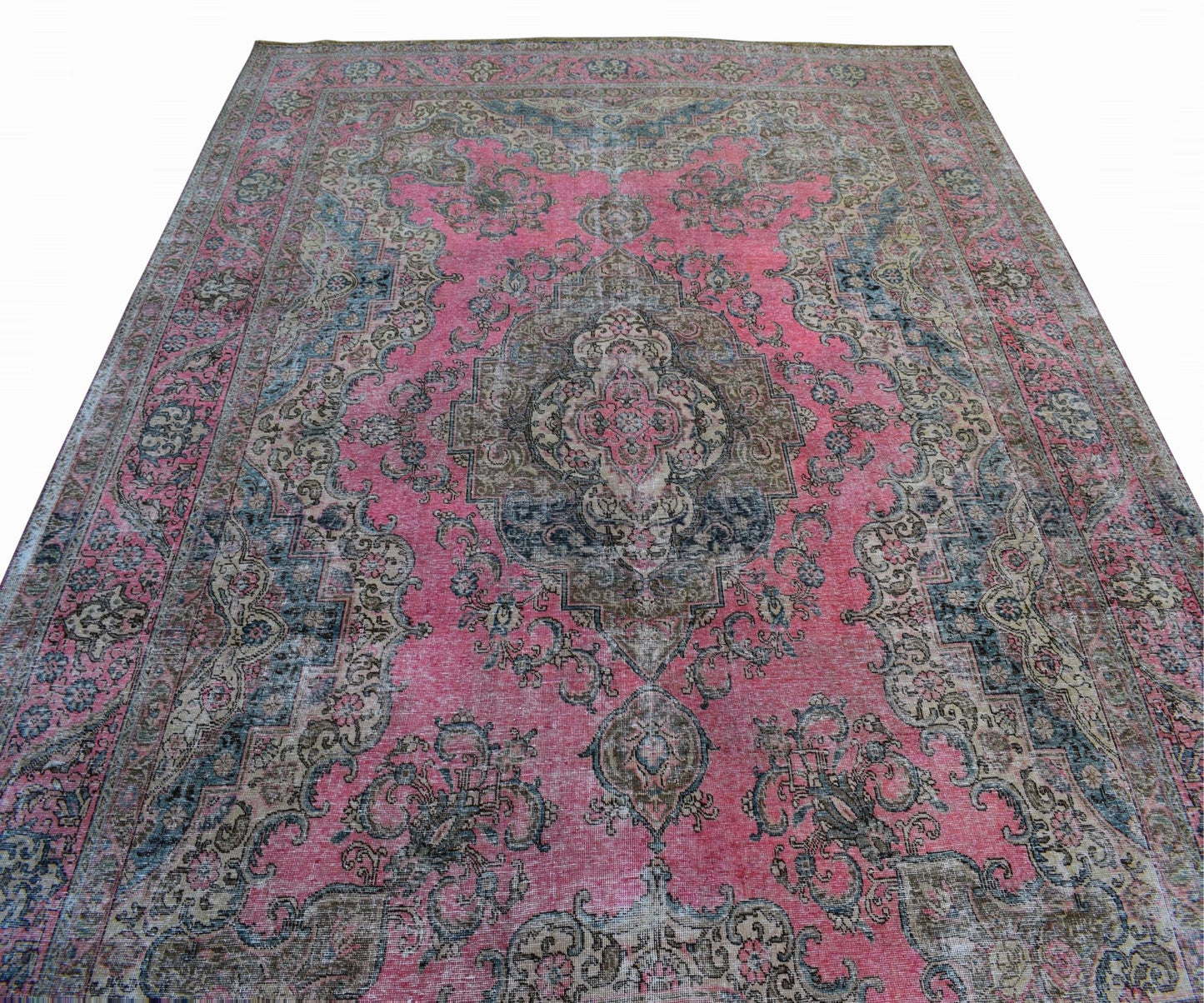 A vintage Persian Tabriz rug featuring a central floral medallion on a faded pink field.
