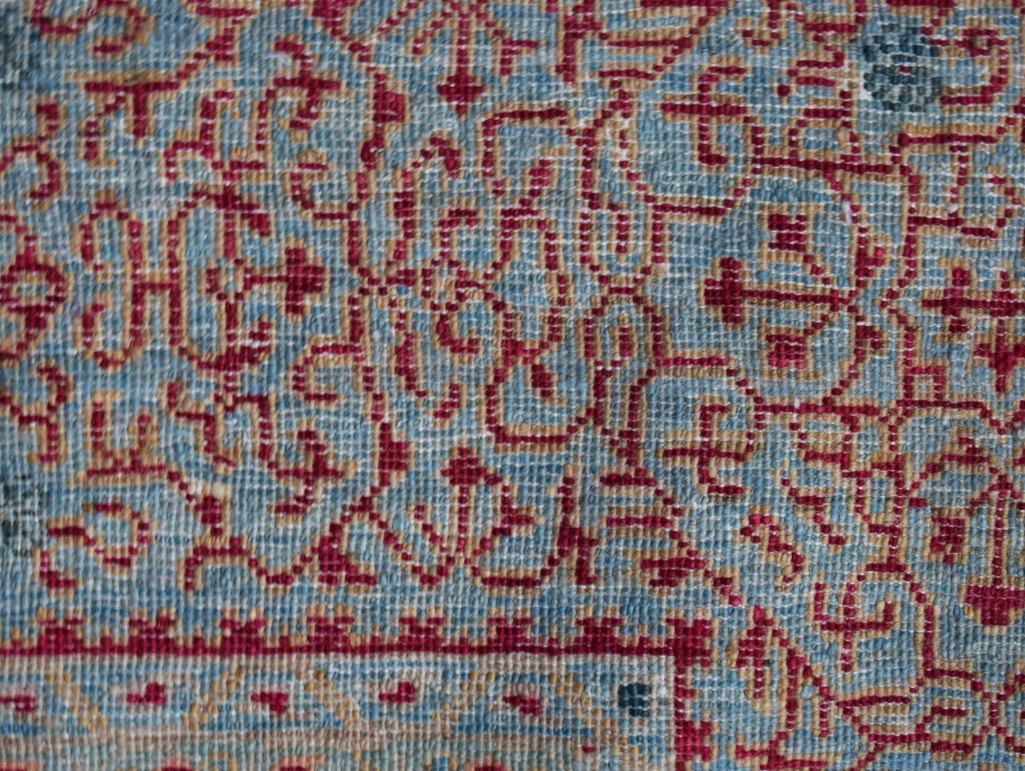 A close-up of a handmade Afghan Balkh rug featuring a detailed red Mamluk pattern on a blue base.
