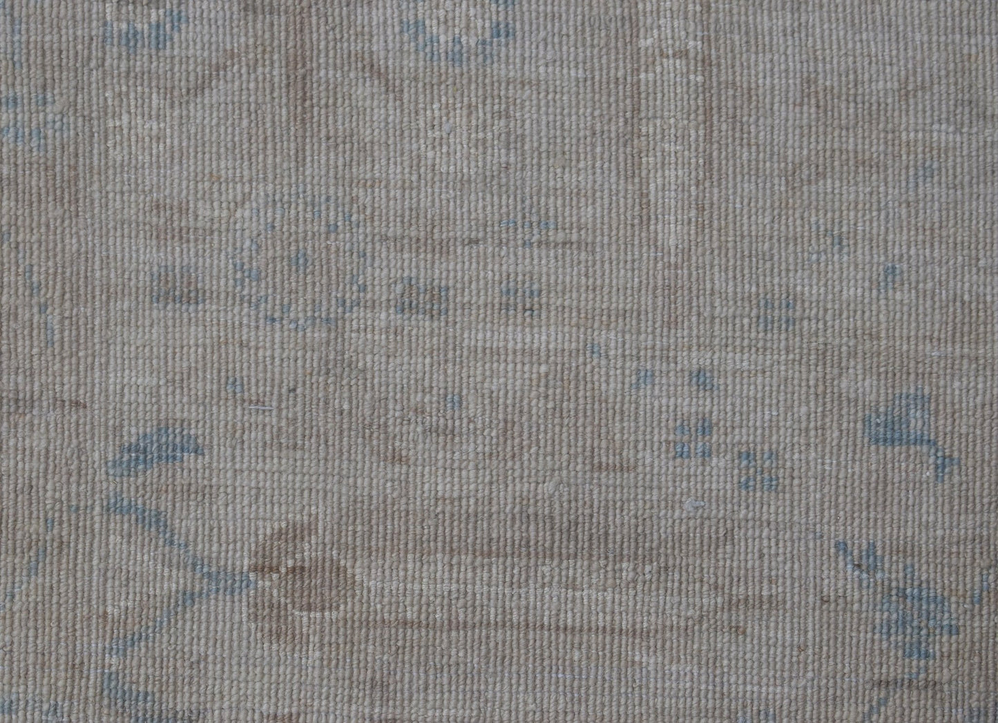 A handwoven Afghan Balkh rug featuring a subtle, traditional pattern in soft beige and blue tones.