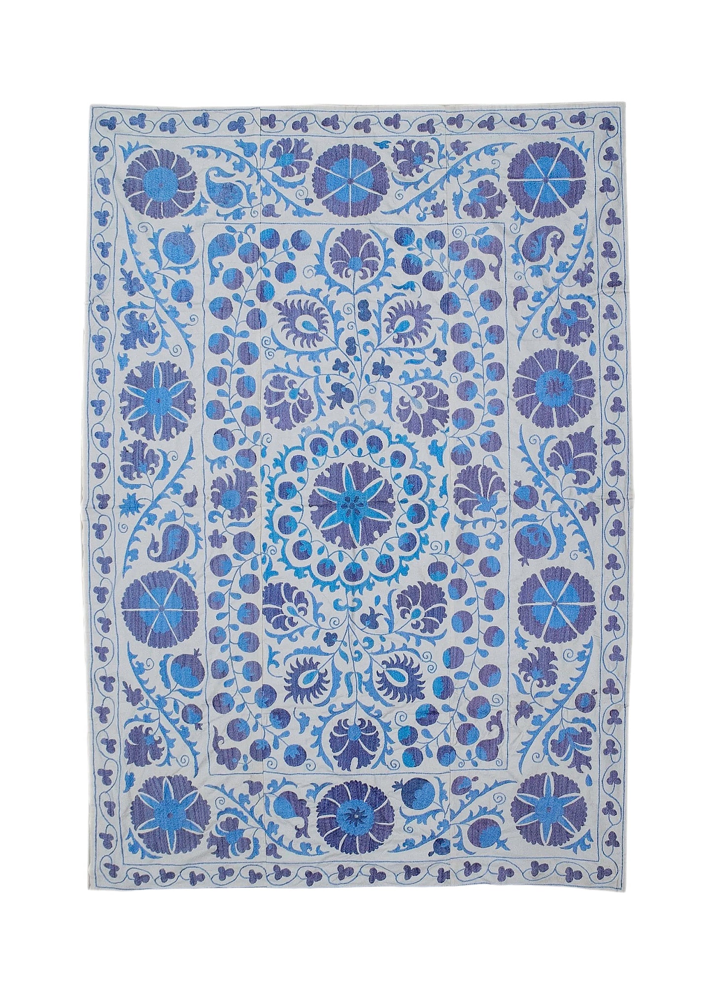 Hand-embroidered Uzbek Suzani featuring blue and purple floral motifs on a light cotton base.