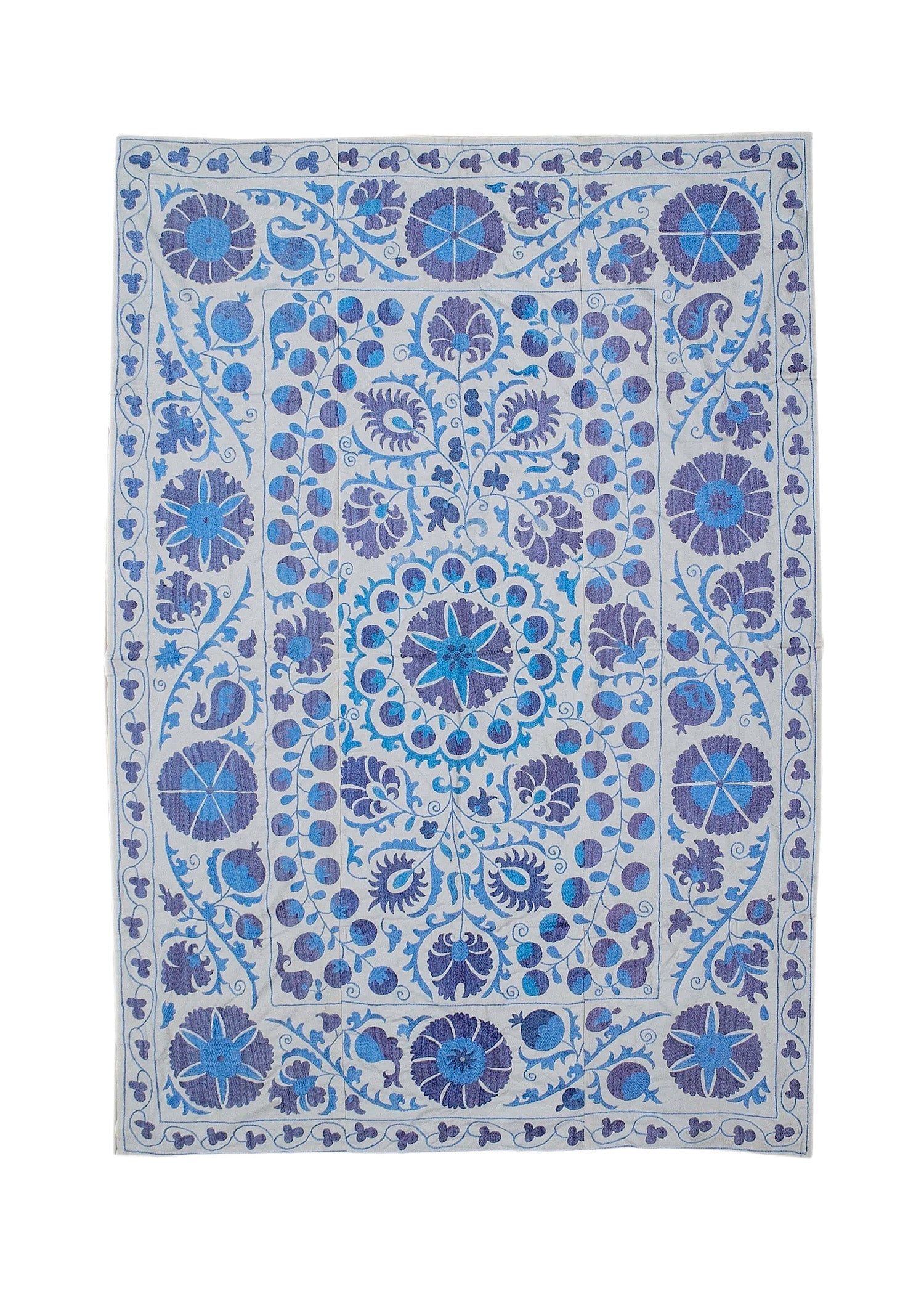 Hand-embroidered Uzbek Suzani featuring blue and purple floral motifs on a light cotton base.