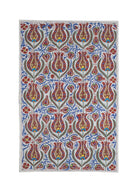 A rectangular Uzbek suzani textile featuring intricate floral embroidery in red, blue, and gold.