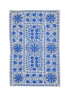 A rectangular Uzbek suzani featuring blue floral and pomegranate embroidery on a white cotton base.