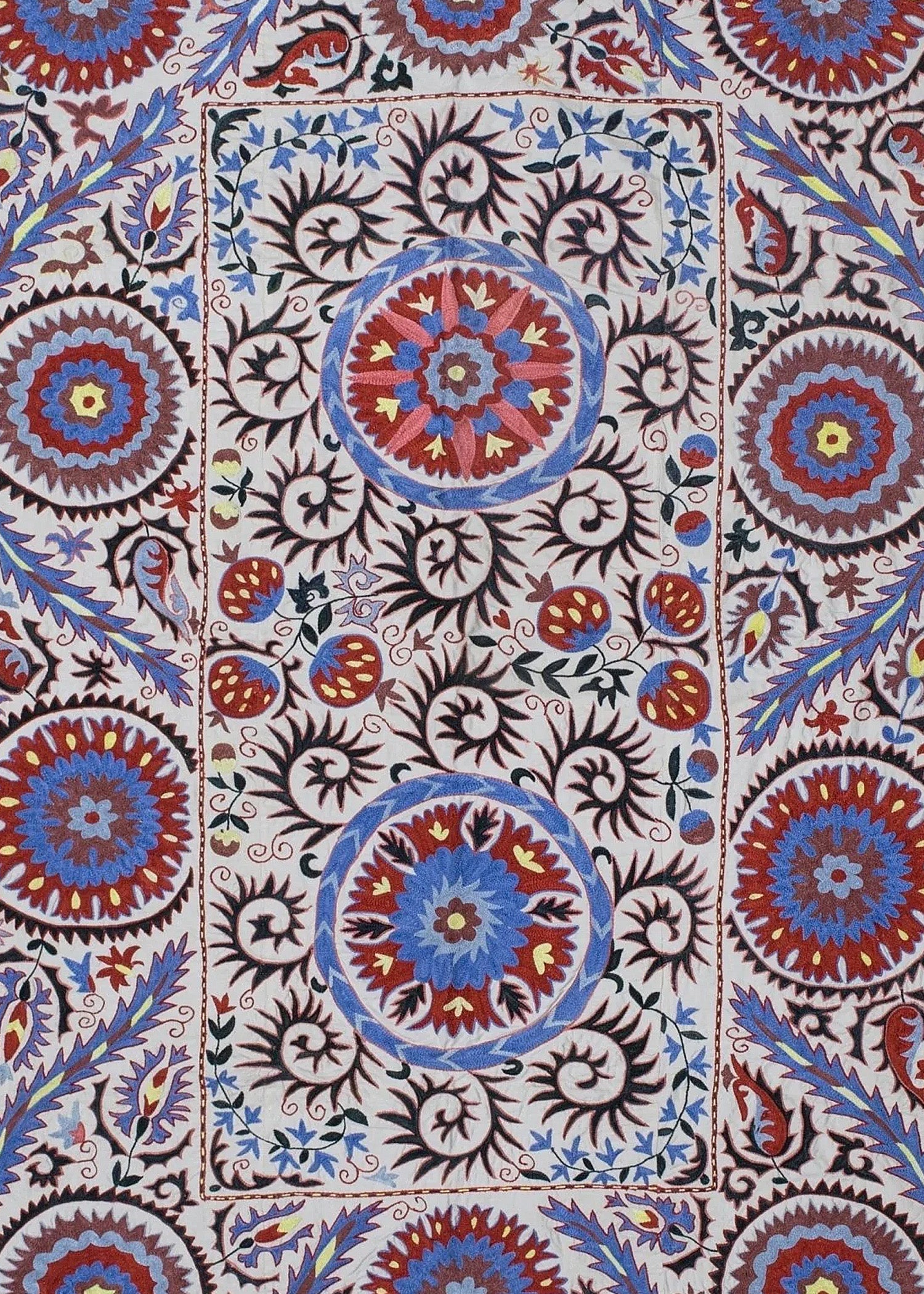 Hand-embroidered Uzbek Suzani textile featuring intricate floral and circular motifs in silk.