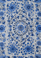 Hand-embroidered Uzbek suzani featuring intricate blue floral and pomegranate motifs on cotton.