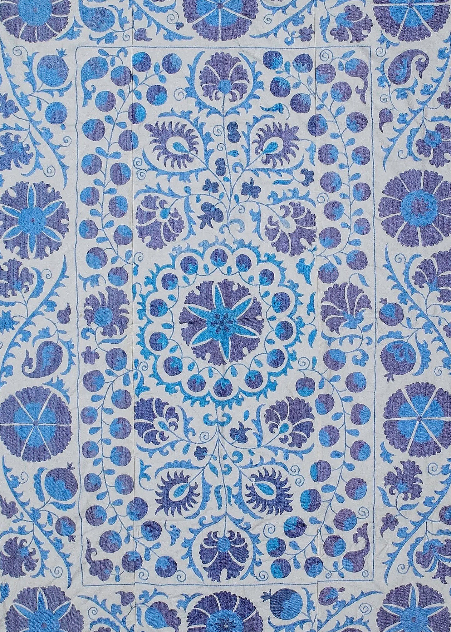Hand-embroidered Uzbek Suzani textile featuring intricate blue and purple floral and fruit motifs.