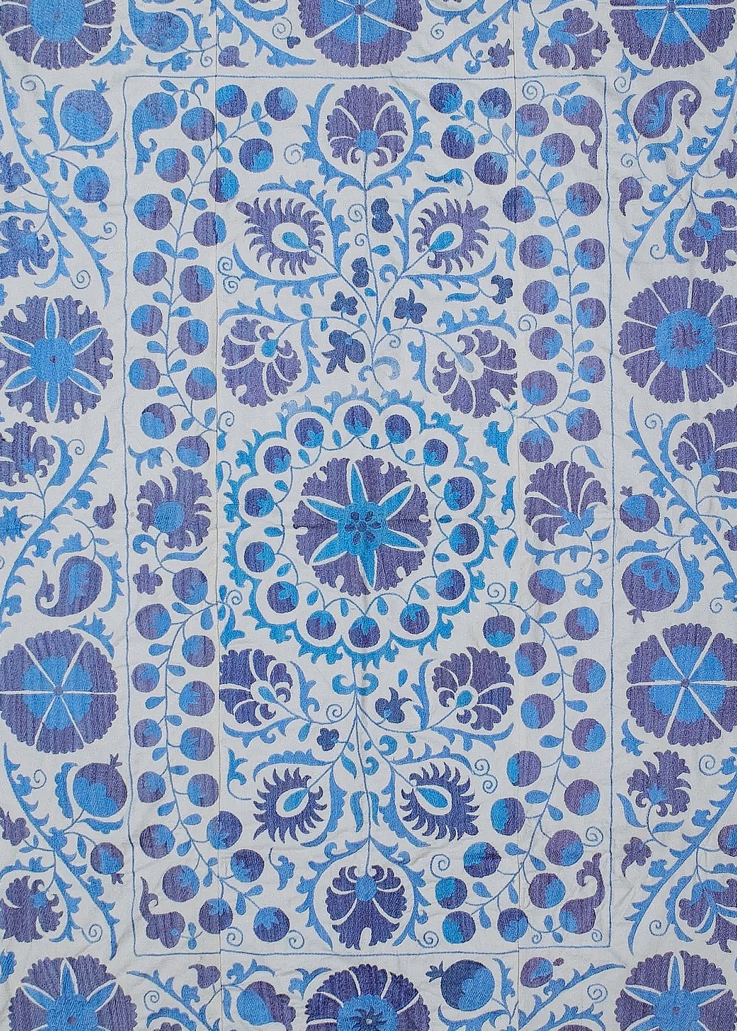 Hand-embroidered Uzbek Suzani textile featuring intricate blue and purple floral and fruit motifs.