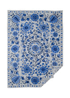 Hand-embroidered Uzbek Suzani featuring blue floral and botanical motifs on a light cotton base.