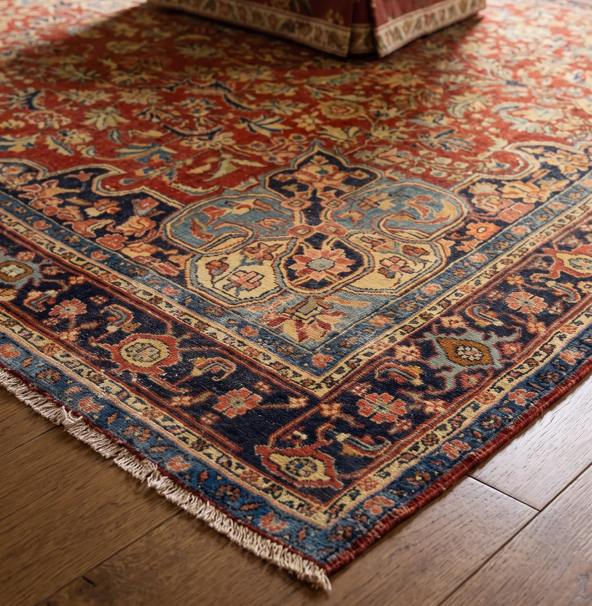 Hand-knotted Persian Kashan rug featuring a red field, blue floral medallion, and intricate vine motifs on timber flooring.