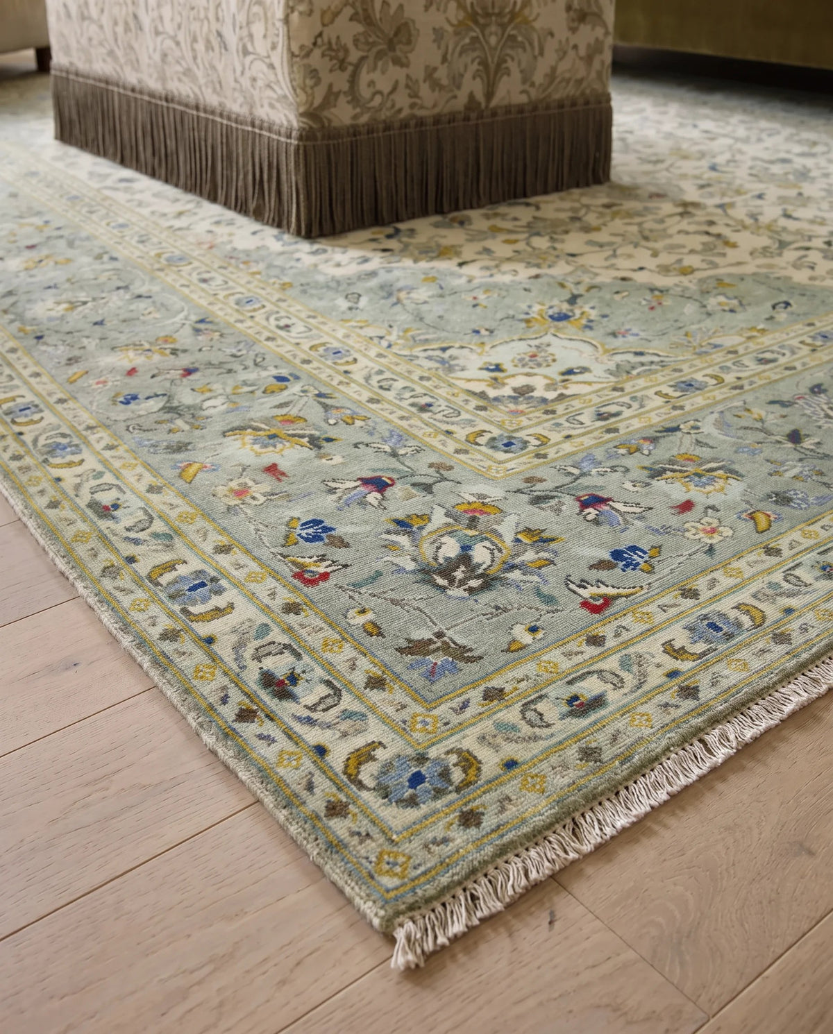 Hand-knotted Persian Kashan rug featuring a sage green floral field, intricate central medallion, and a delicate knotted fringe.