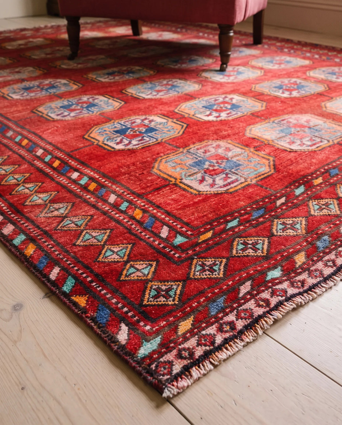 Hand-knotted Turkmen Ersari rug in deep red with blue elephant's foot guls, geometric borders, and wool fringe.