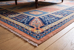 Hand-knotted Afghan Balkh rug with a blue and peach floral pattern, fine wool pile, and a short knotted fringe.