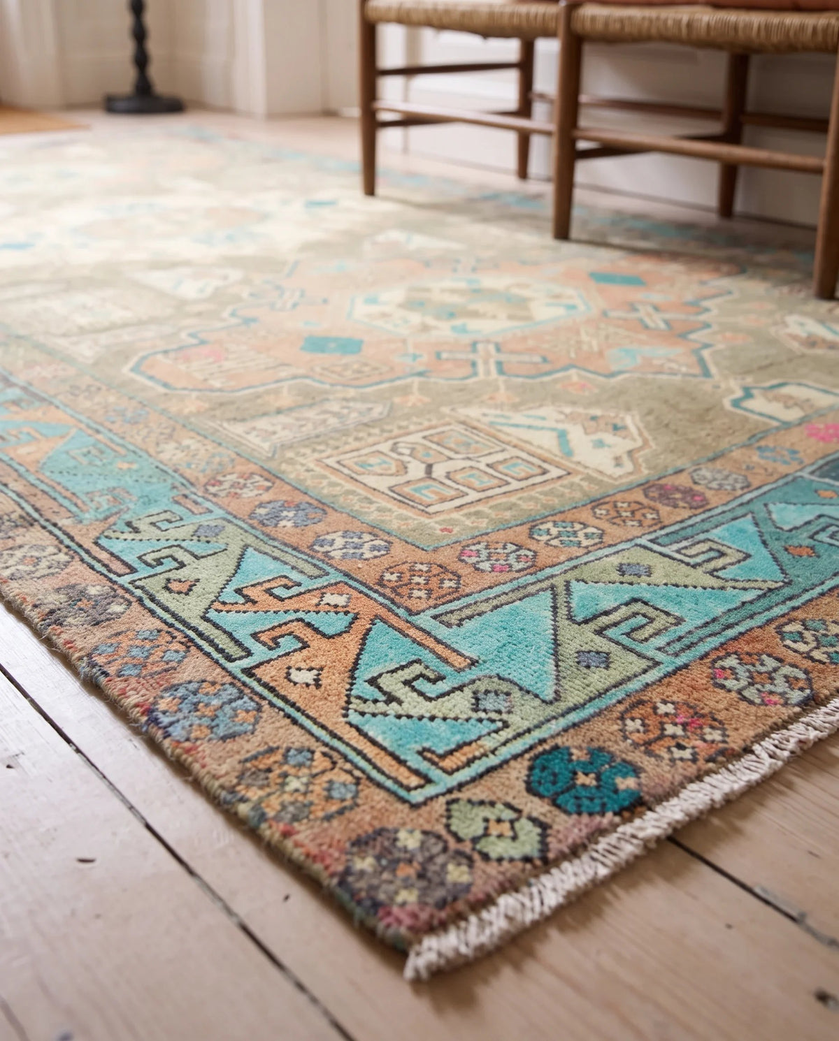 Vintage Persian Meshkin rug with a geometric medallion pattern in faded indigo, madder red, and earthy tones on wood floors.