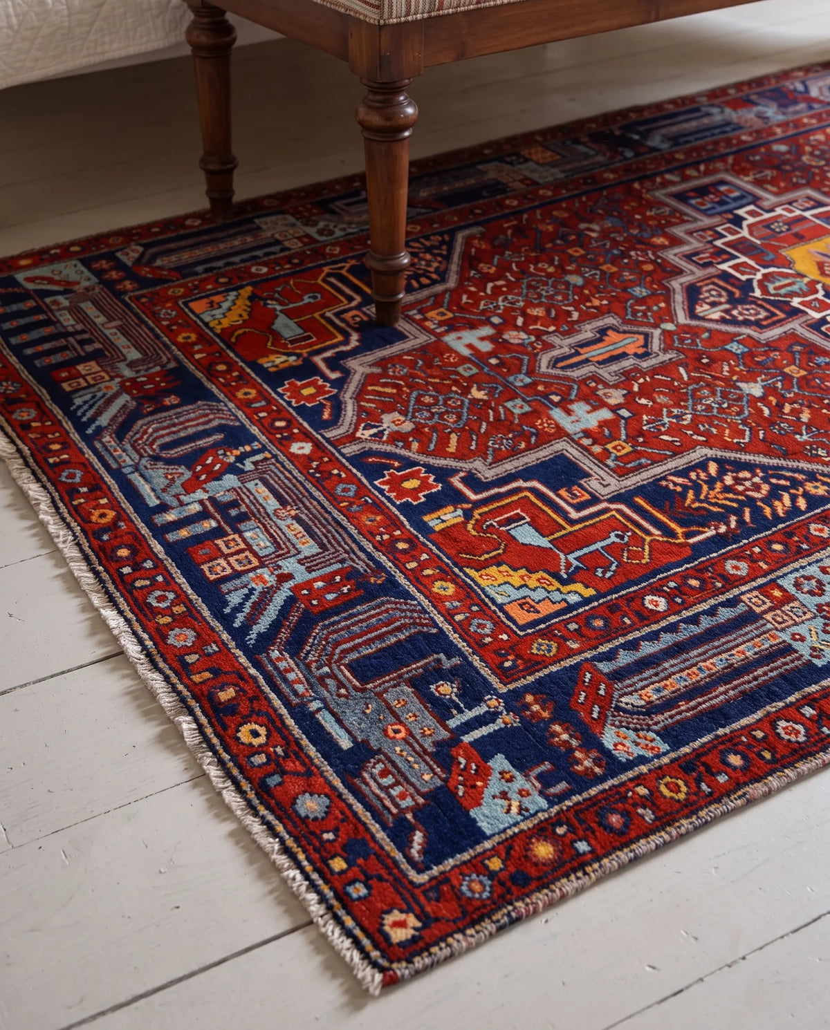 Hand-knotted Persian Hamadan rug featuring red and blue geometric medallions and tribal motifs on a white timber floor.
