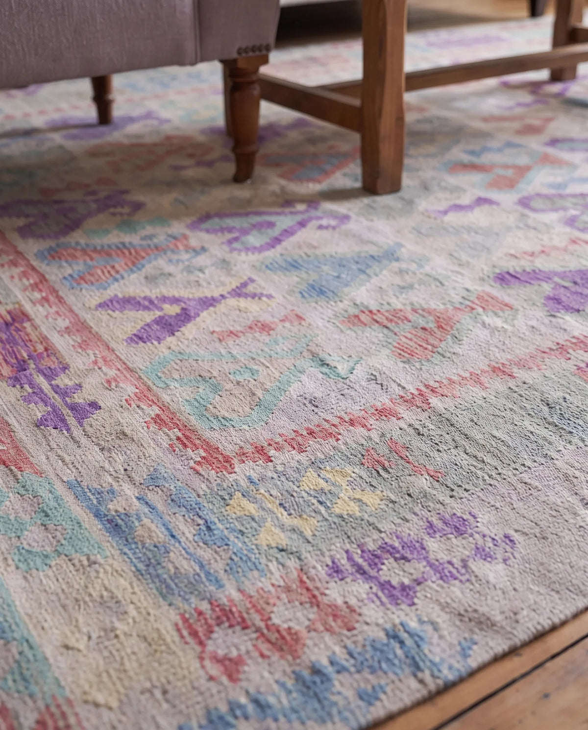 Handwoven Afghan Maimana kilim in wool with a flatweave texture and colourful geometric patterns under wooden furniture.