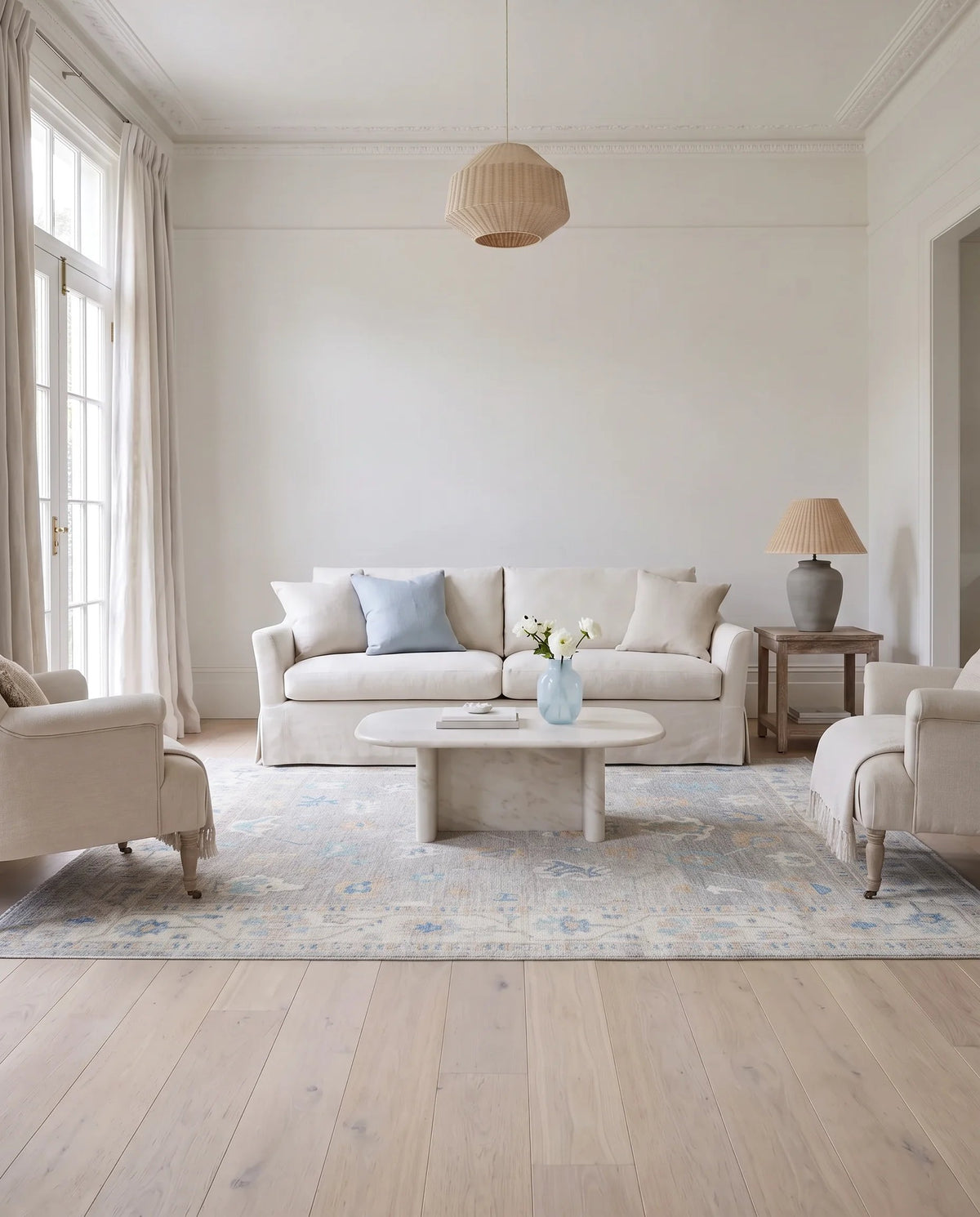 Hand-knotted Afghan Oushak rug in soft blue and cream tones with a traditional floral pattern in a bright living room.