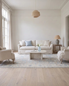 Hand-knotted Afghan Oushak rug in soft blue and cream tones with a traditional floral pattern in a bright living room.