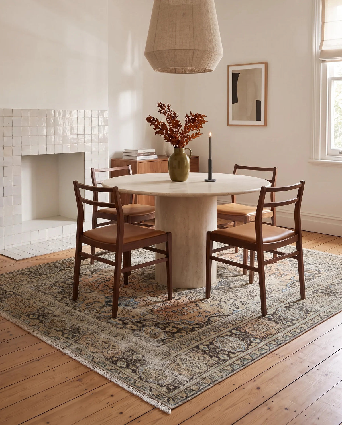 Vintage Persian Moud rug with intricate floral patterns in muted tones, styled under a round dining table on timber floors.
