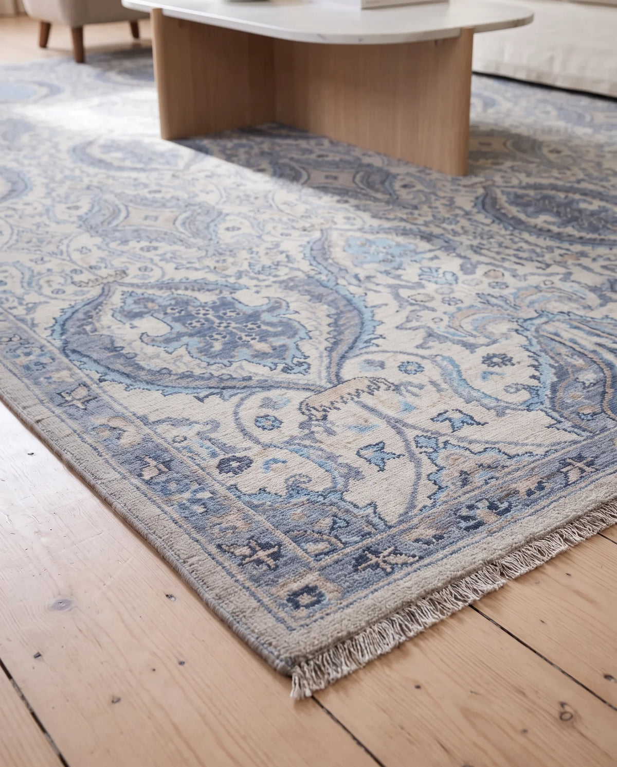 Hand-knotted Afghan Balkh rug with blue and cream floral patterns and a fine fringe on a timber floor.