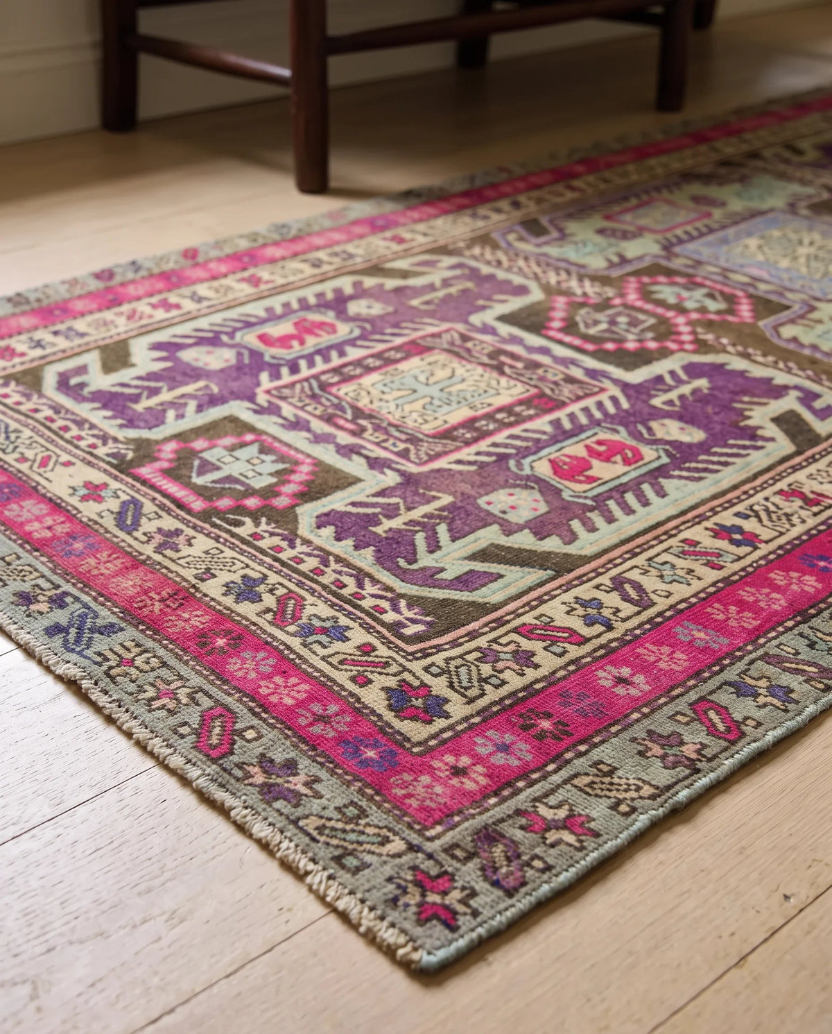Vintage wool Ardabil runner featuring geometric motifs in vibrant pink, purple, and sage green on a timber floor.