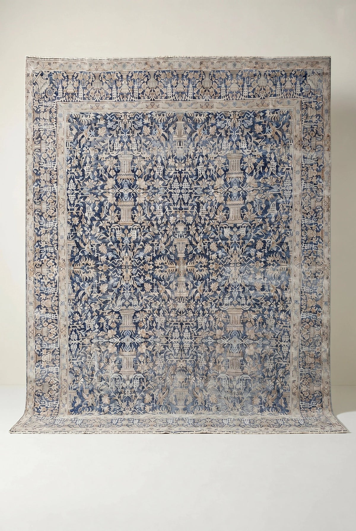 Vintage Persian Kerman rug featuring an intricate blue and beige floral pattern with a central urn motif and flat pile.