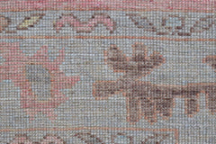 A close-up view of a handwoven wool runner rug featuring a transitional floral pattern in soft tones.