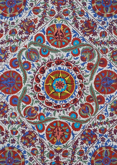 Hand-embroidered Uzbek Suzani textile featuring vibrant floral and celestial motifs on cotton.