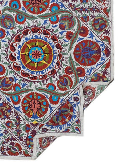 Hand-embroidered Uzbek Suzani textile featuring vibrant floral and celestial motifs on cotton.