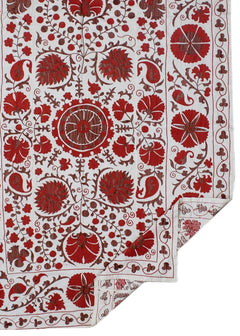 A white cotton textile featuring intricate red floral and paisley embroidery in a traditional style.