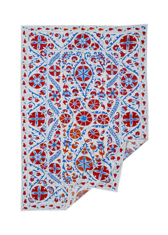 Hand-embroidered Uzbek Suzani textile featuring red and blue floral motifs on a white cotton base.