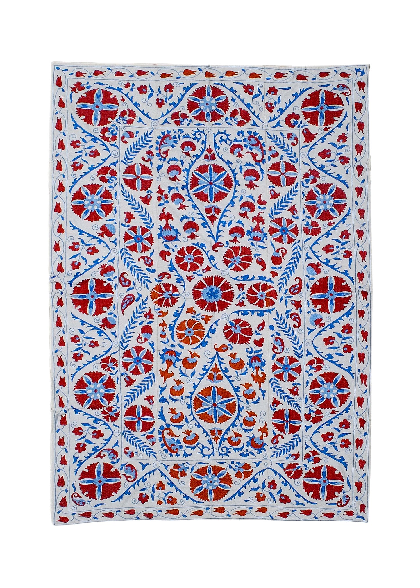 Hand-embroidered Uzbek Suzani textile featuring red and blue floral motifs on a white cotton base.
