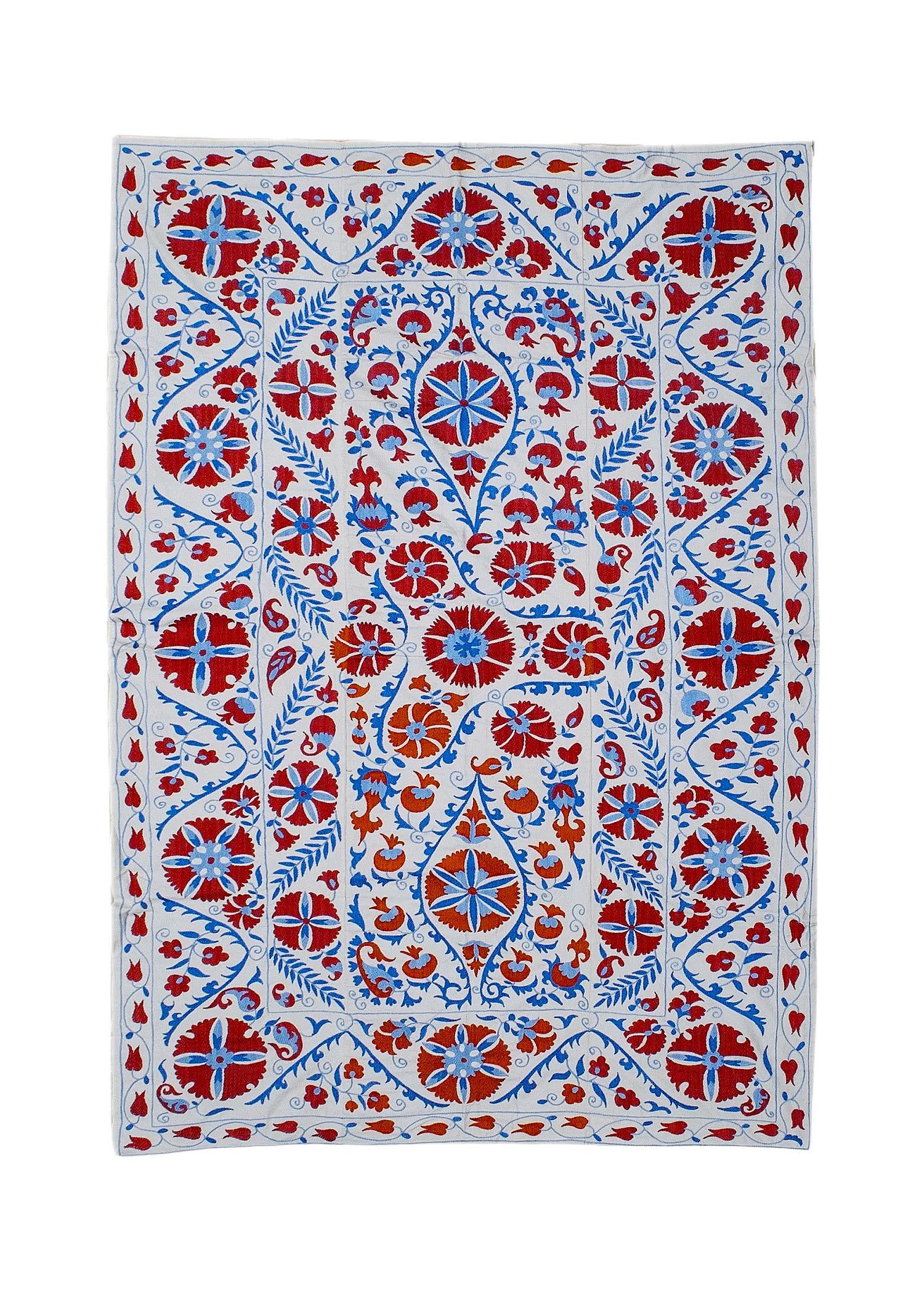 Hand-embroidered Uzbek Suzani textile featuring red and blue floral motifs on a white cotton base.