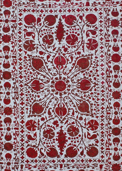 A hand-embroidered Uzbek suzani featuring intricate red floral motifs on a white cotton background.
