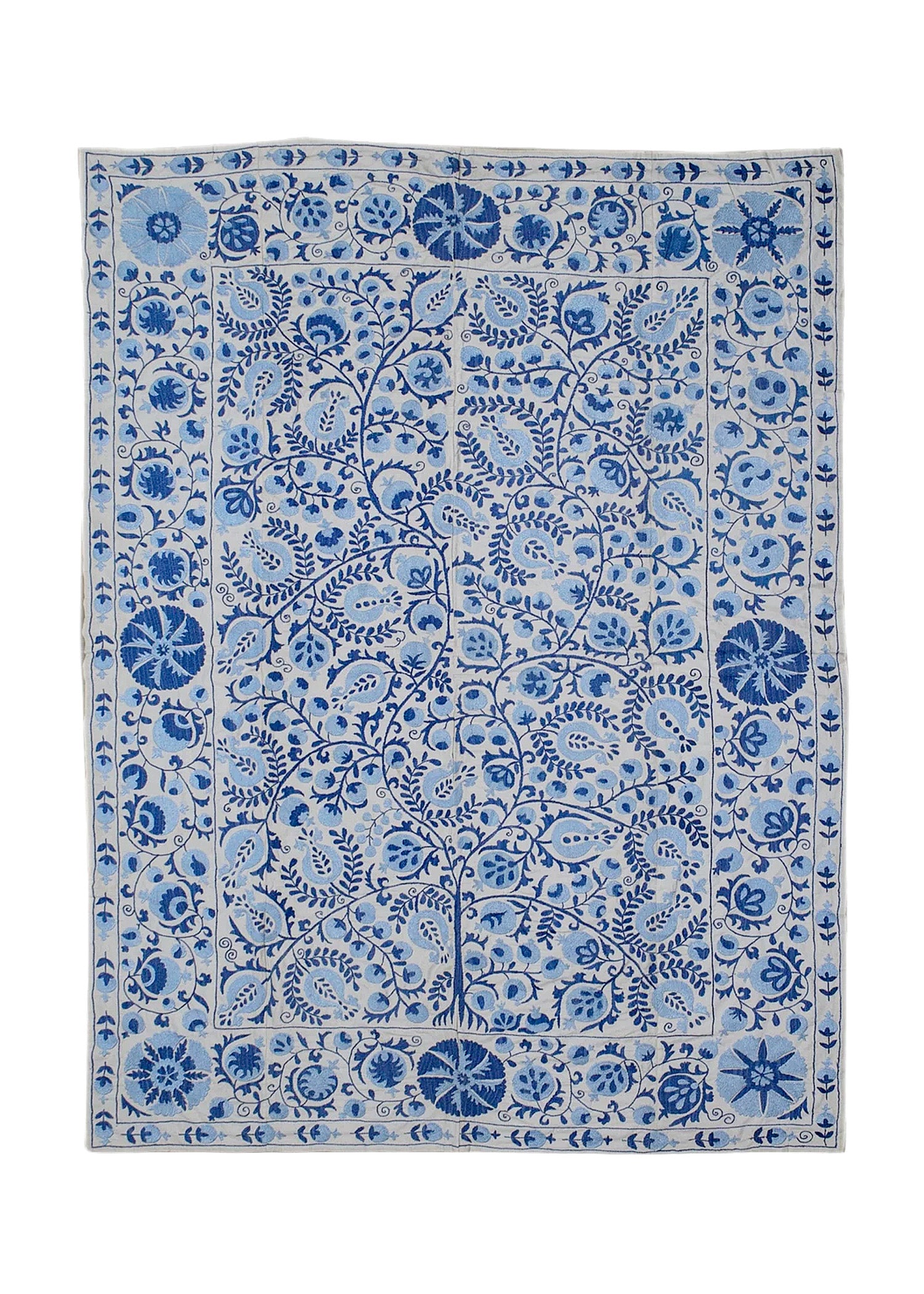 A rectangular Uzbek suzani featuring intricate blue floral and vine embroidery on a white base.
