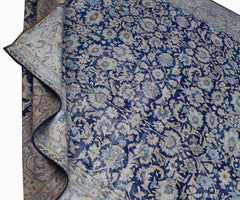 A vintage Persian Kerman rug featuring an intricate blue and cream floral pattern.