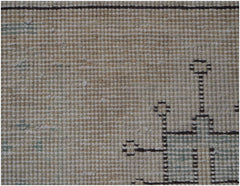 A close-up view of a vintage Persian Kerman rug featuring a geometric pattern on a beige field.