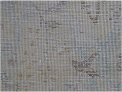 A close-up of a vintage Persian Kerman rug featuring a faded floral pattern in soft muted tones.