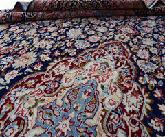 A vintage Persian Kerman rug featuring an intricate floral medallion on a deep blue background.