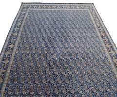 A vintage Persian Kerman rug featuring an all-over blue paisley pattern with a detailed border.
