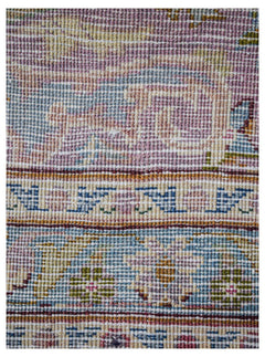 A close-up of a vintage Persian Kerman runner featuring intricate floral patterns in soft colors.