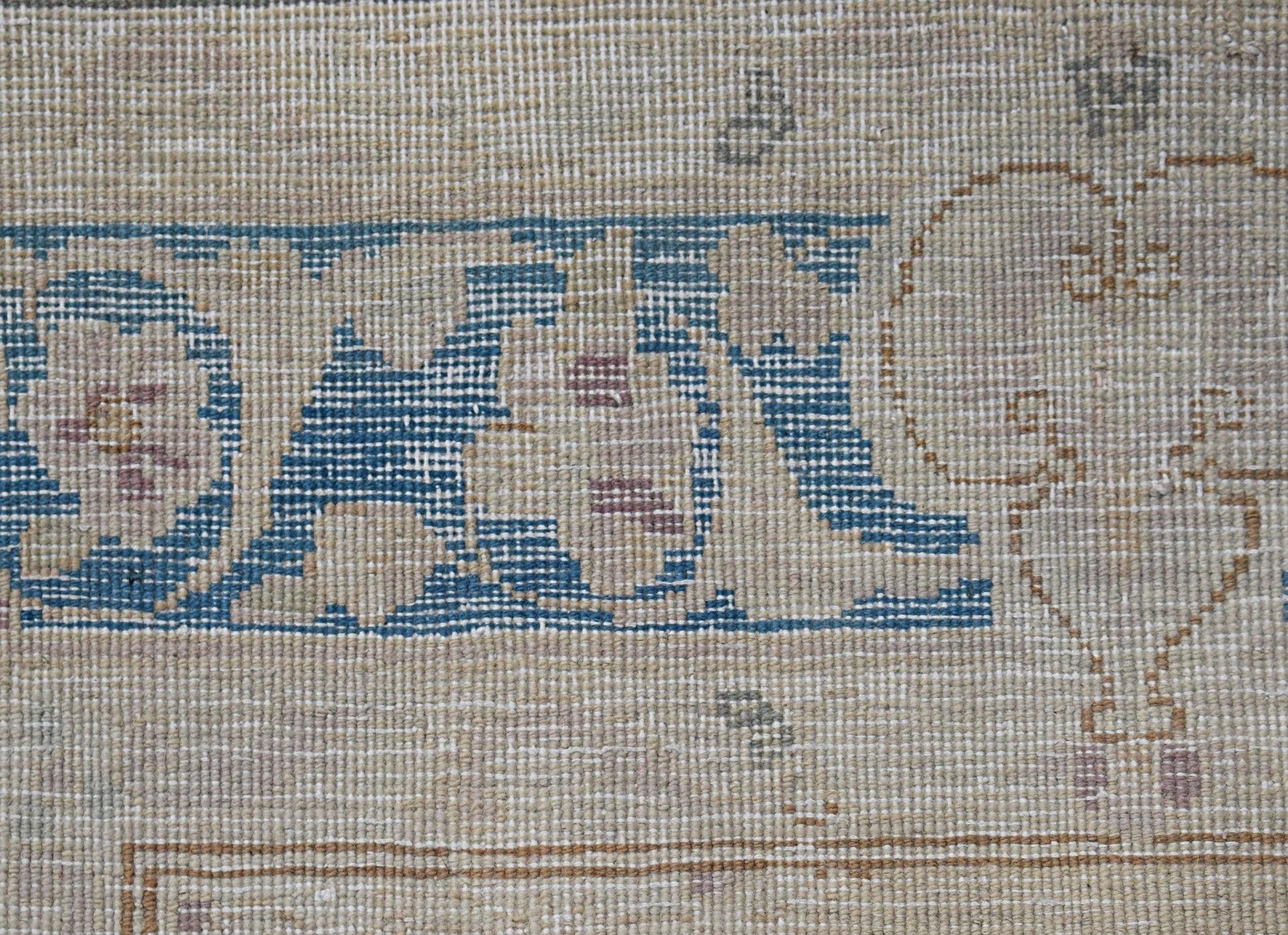 A close-up of a vintage Persian Kerman runner featuring intricate blue and beige floral patterns.
