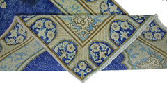 A vintage Persian Kerman runner featuring a blue and cream floral pattern with a folded corner.