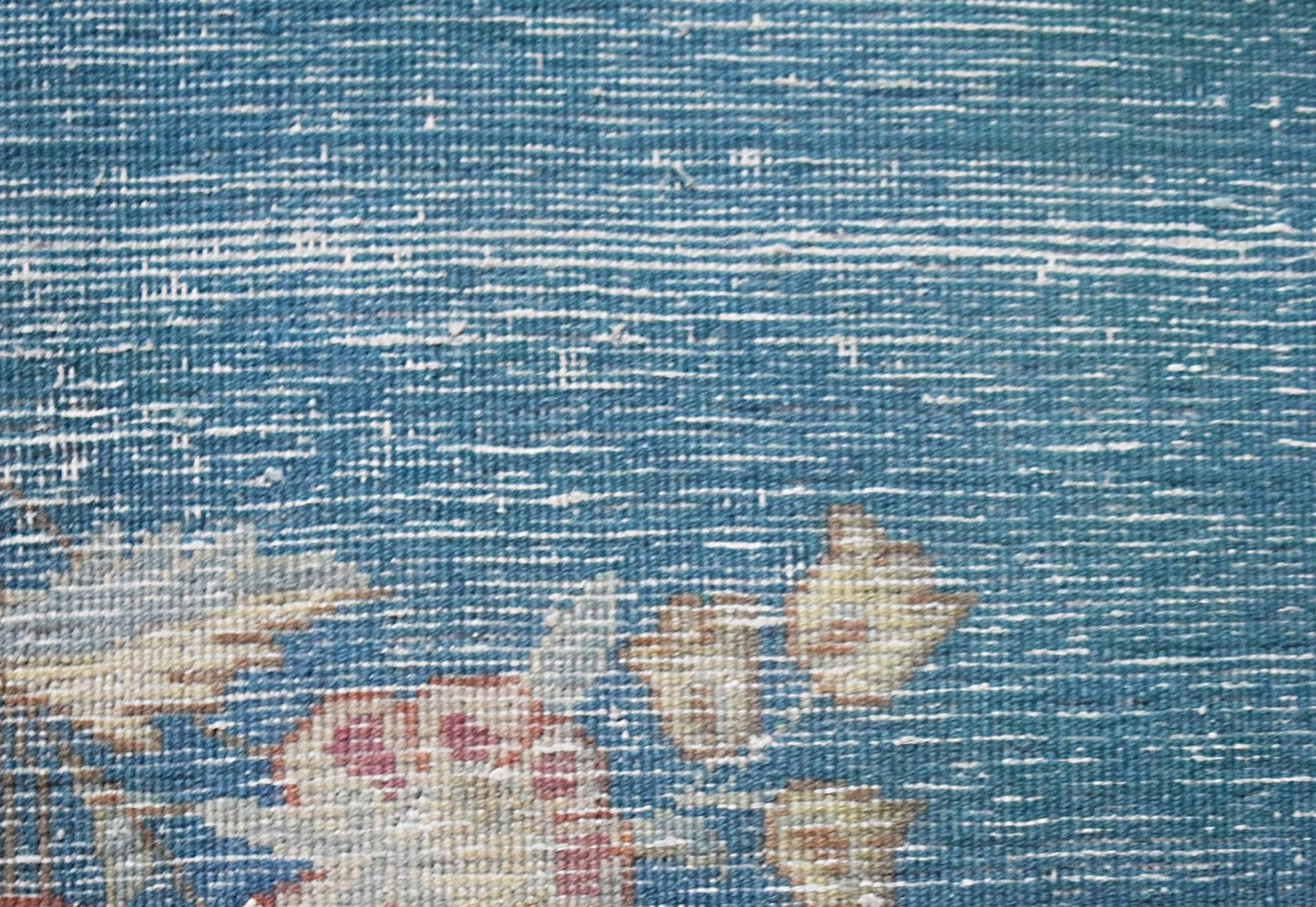 A close-up of a vintage Persian Kerman runner featuring intricate floral patterns on a blue field.