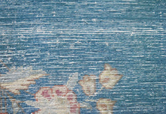 A close-up of a vintage Persian Kerman runner featuring intricate floral patterns on a blue field.