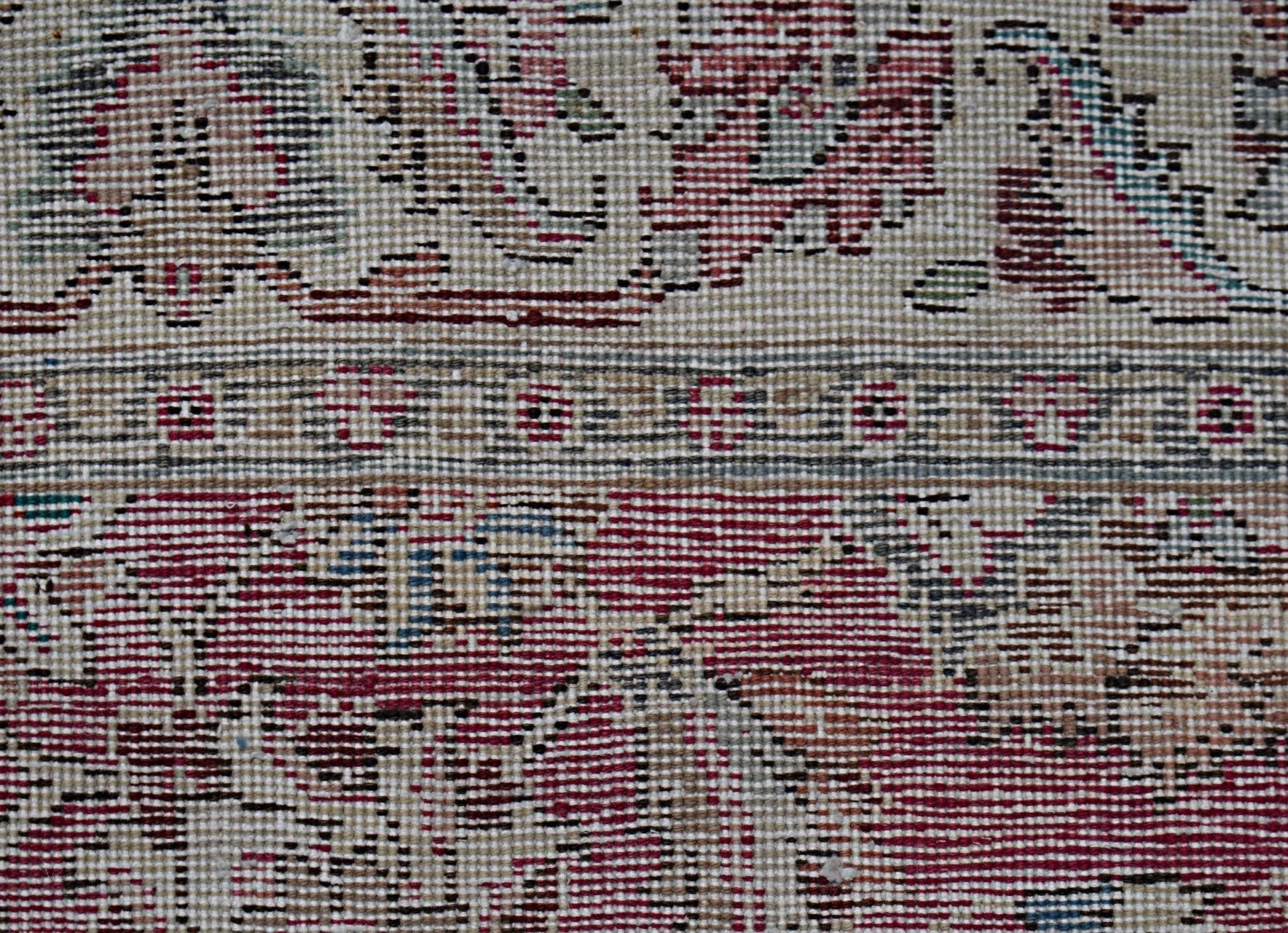A close-up view of a vintage Persian Kerman runner featuring intricate floral patterns in red.